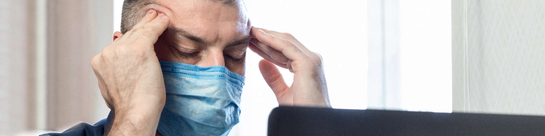 Maximizing Your Income As a Caregiver, Man in a Face Mask Rubbing His Temples