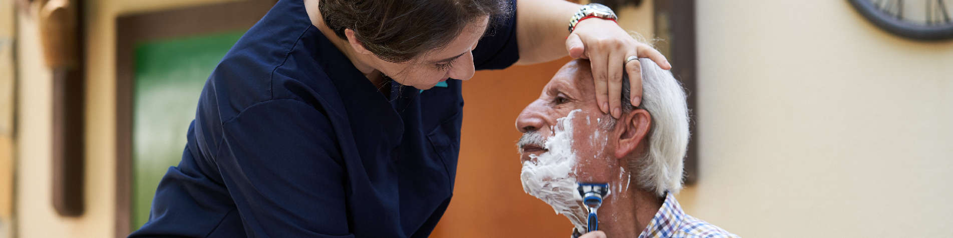 Caregiver Shaving Their Elderly Client's Face